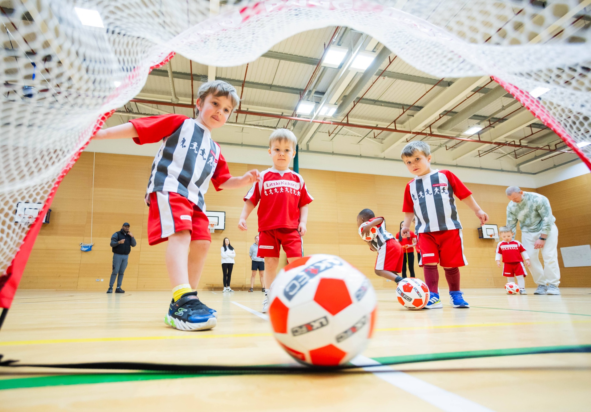 Group of children dribbling footballs through cones at training
