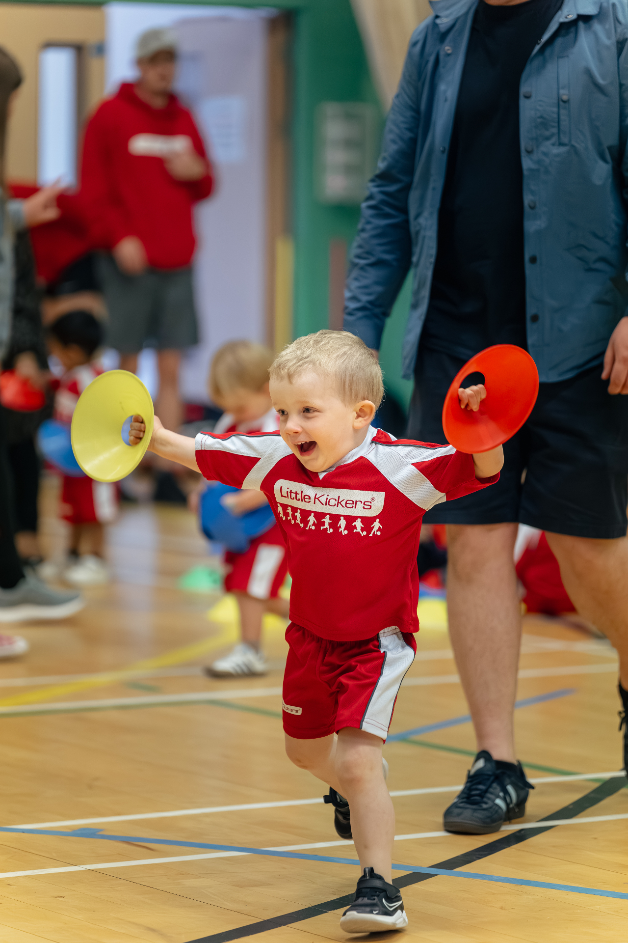 Smiling young child holding training cones during a Little Kickers session